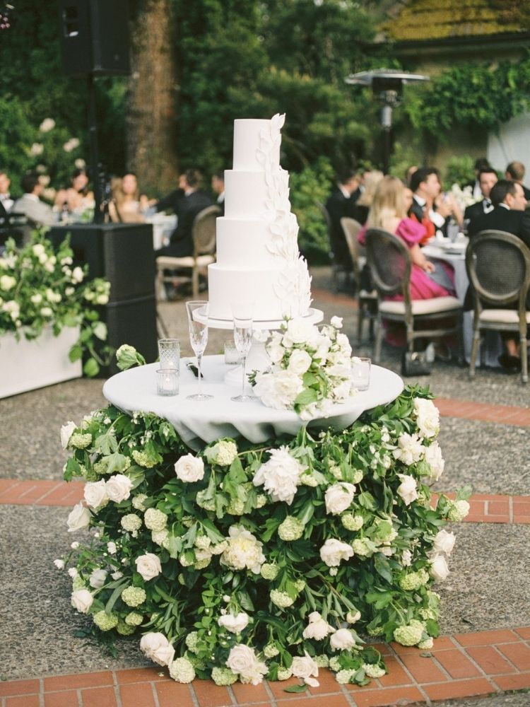 white wedding cake on greenery-covered cake table