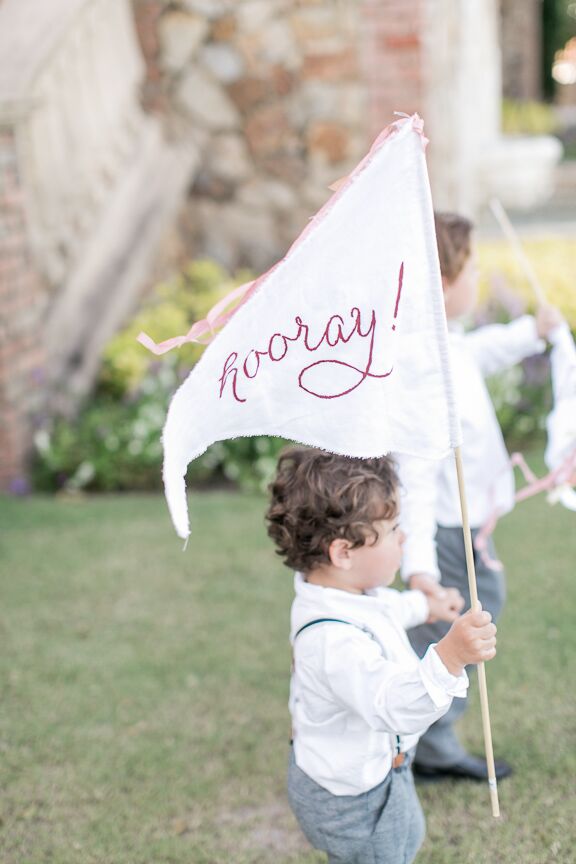 Michelle and Michael’s son, Oliver, had just started to walk when he served as the couple’s ring bearer. Complete with a white shirt and Zara suspenders, he was escorted down the aisle by two of his aunts. The couple’s nephews walked ahead holding  “Yay” and “Hooray” stitched flags.