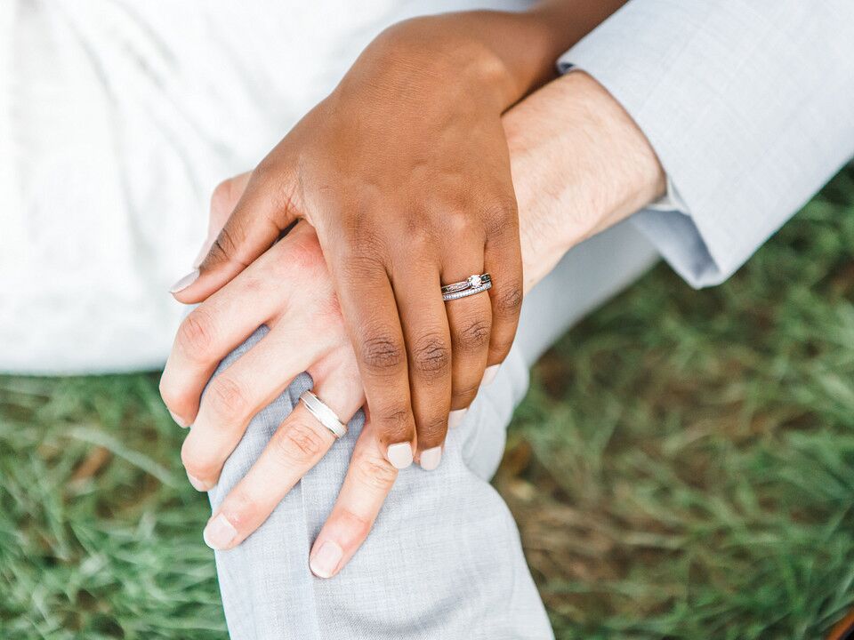 Couple holding hands showing off wedding and engagement rings