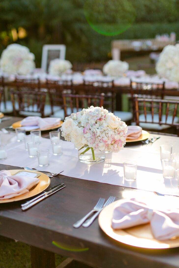 Lauren and Andy really wanted their tablescapes to make an impact against the lush hedges. So they worked with Signature Florals to design just that. Overflowing arrangements of white and pink hydrangeas as well as blush garden roses lined every blush silk runner along the cherrywood tables.