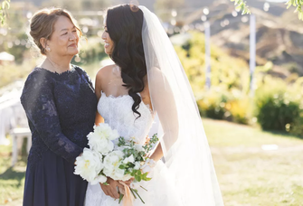 A bride and mother of the bride smile at each other.