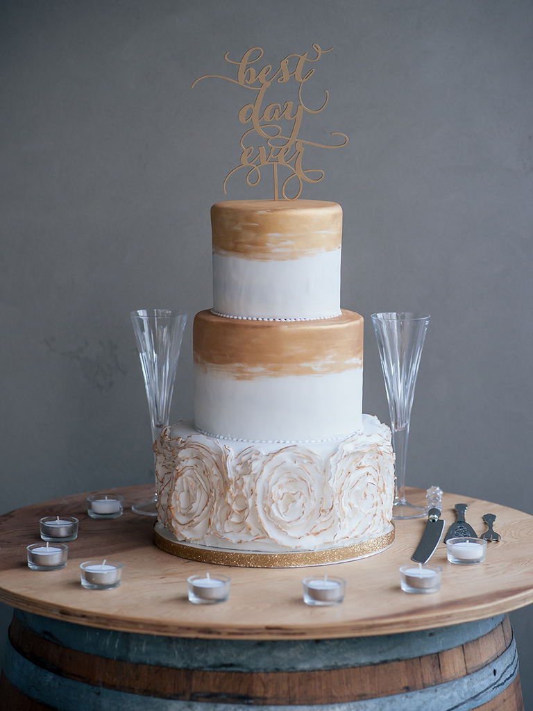 Three tier white wedding cake with gold detailing