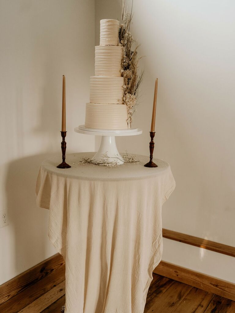 Textured three-tier white wedding cake with clusters of boho flowers