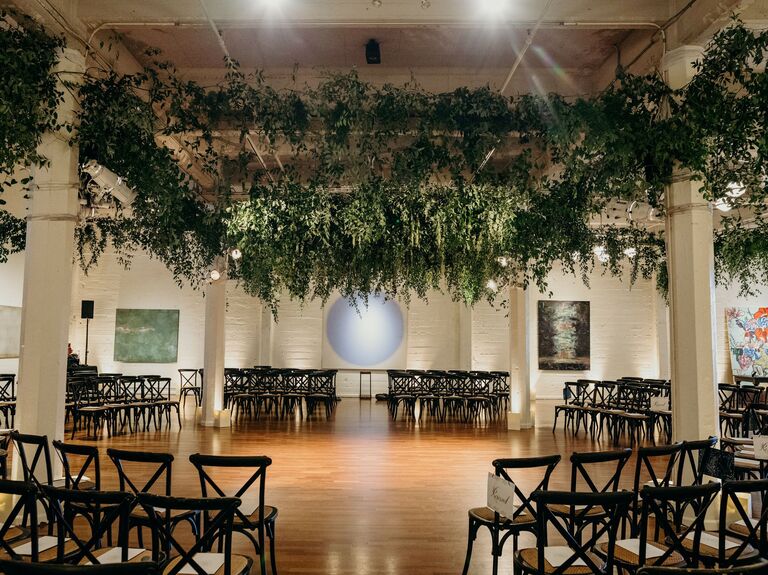 indoor wedding ceremony venue with chairs circling the altar and greenery vines covering the ceiling