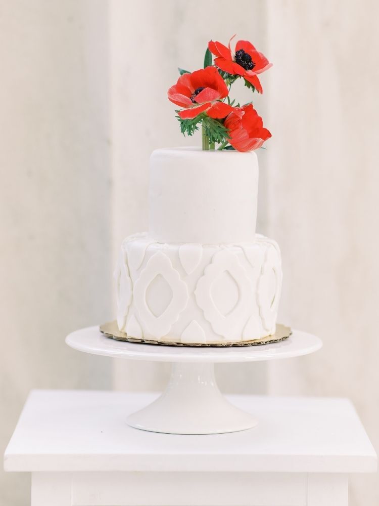 white wedding cake decorated with red flowers