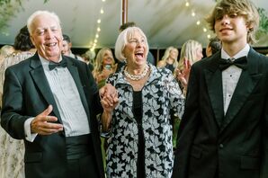 Guests in Black-Tie Attire Enjoy a Tented Garden Wedding Reception Under String Lights