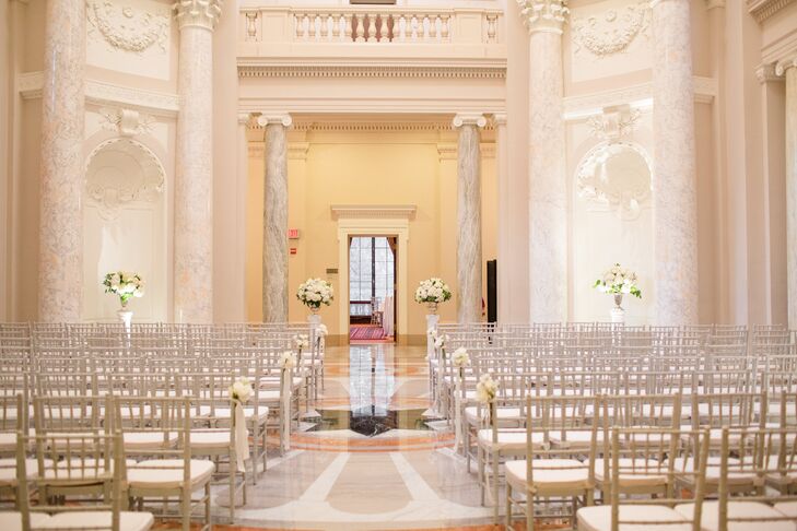 The ceremony was held in the rotunda at the Carnegie Institute of Washington. The hall has tall marble pillars and a clean, white color scheme, making it a versatile space. Floral arrangements of white hydrangeas on stands at the altar echoed the hall's tall pillars.