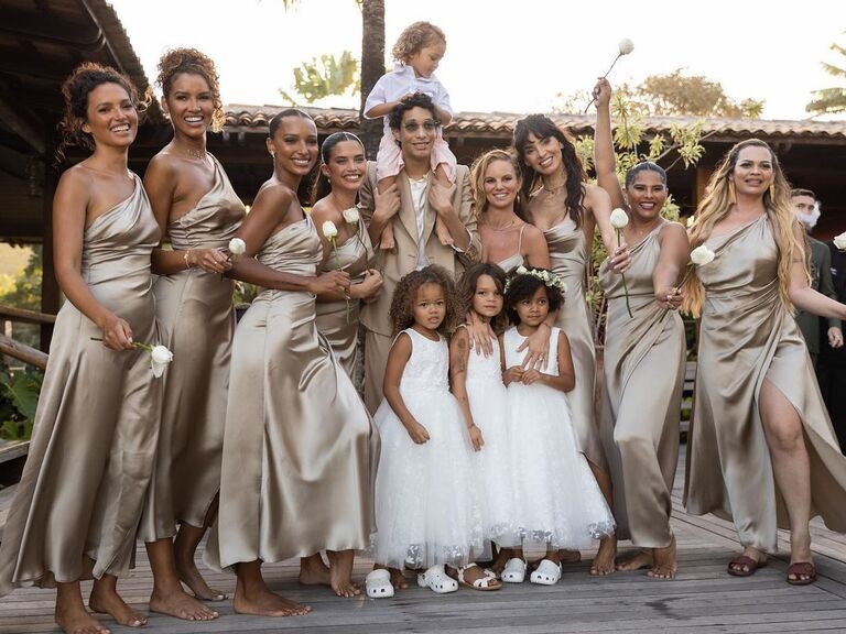 The wedding party smiles for the camera while wearing champagne colored silk gowns. 