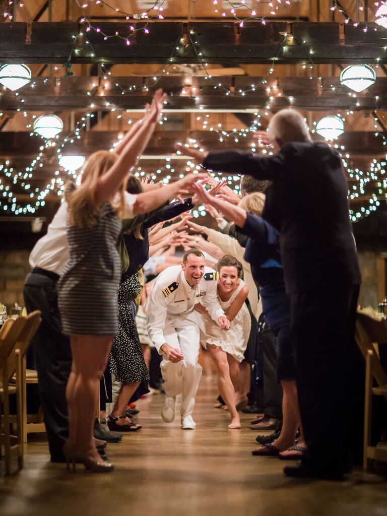 Couple goes through human tunnel at the end of their wedding. 