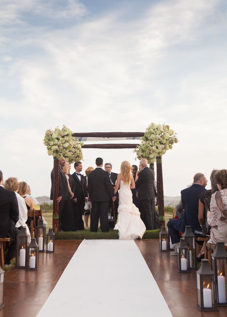 Nora and Michael married under a simple bamboo and tall grass huppah with bunches of hydrangeas, blush spray roses and green vibernum in the corners. The aisle had a white runner and was lined with lamps.