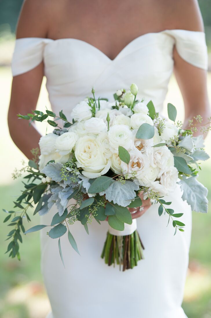 For Rebecca’s walk down the aisle, Dragonfly Events created a standout romantic bouquet filled with fresh white blooms and cool textured accents. The hand-tied arrangement featured roses, ranunculus, liasianthus, dusty miller, snowberry, eucalyptus and bay laurel, and was finished with a length of white silk ribbon.