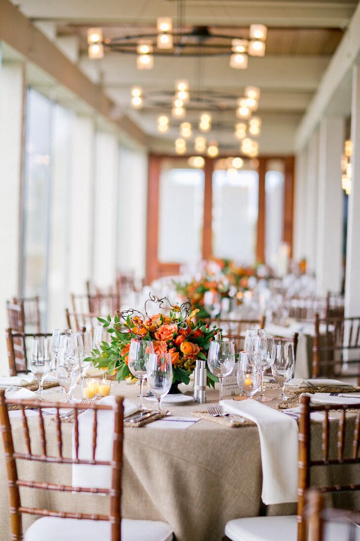The couple brought their rustic coastal wedding to life with light neutral linens and sunny orange flower arrangements.