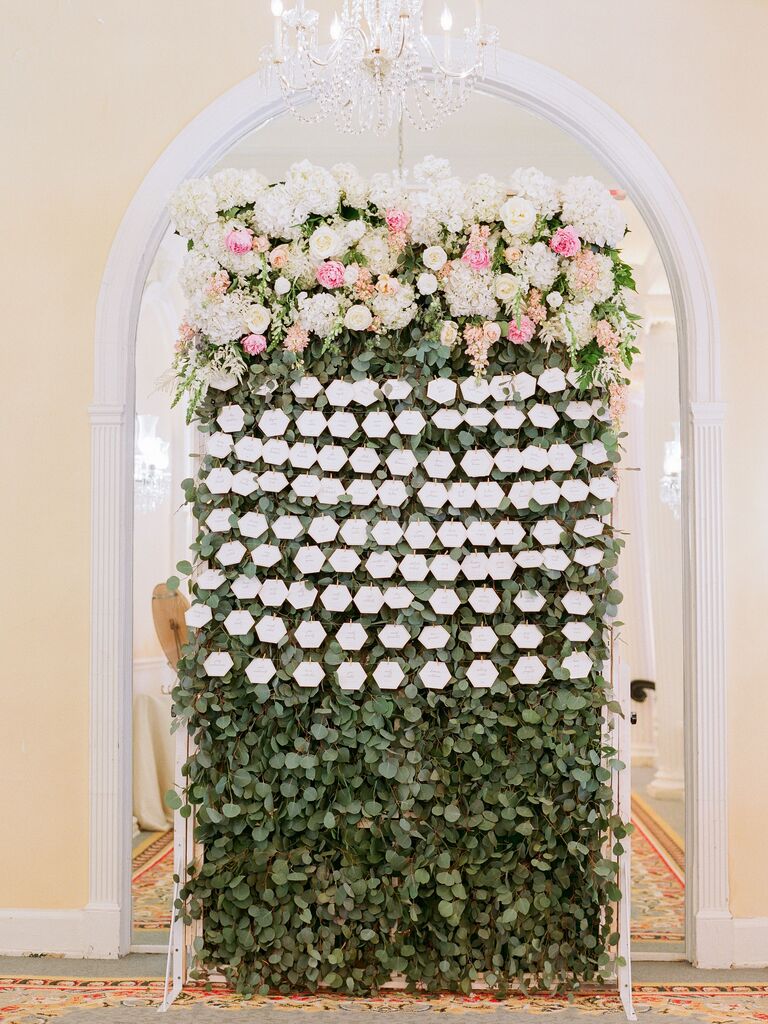 Lush eucalyptus and rose flower wall at a reception.