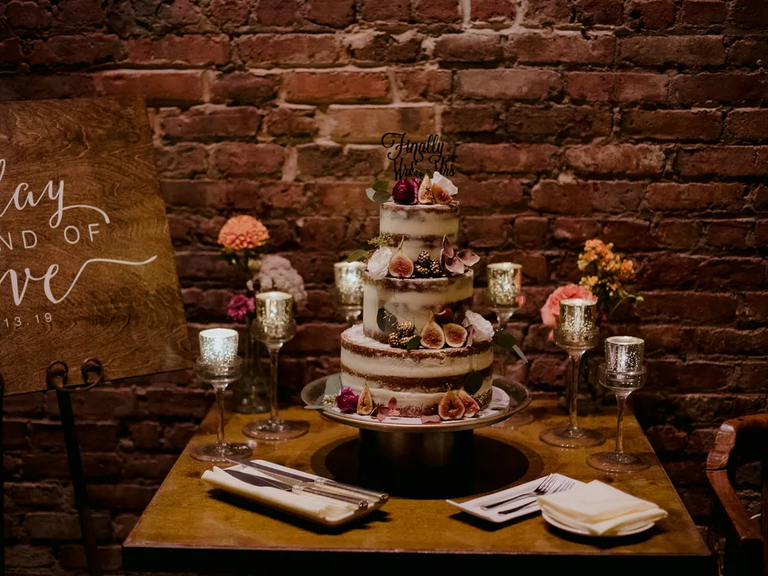 A gorgeous three-tiered naked wedding cake, complemented by cut fresh red figs.