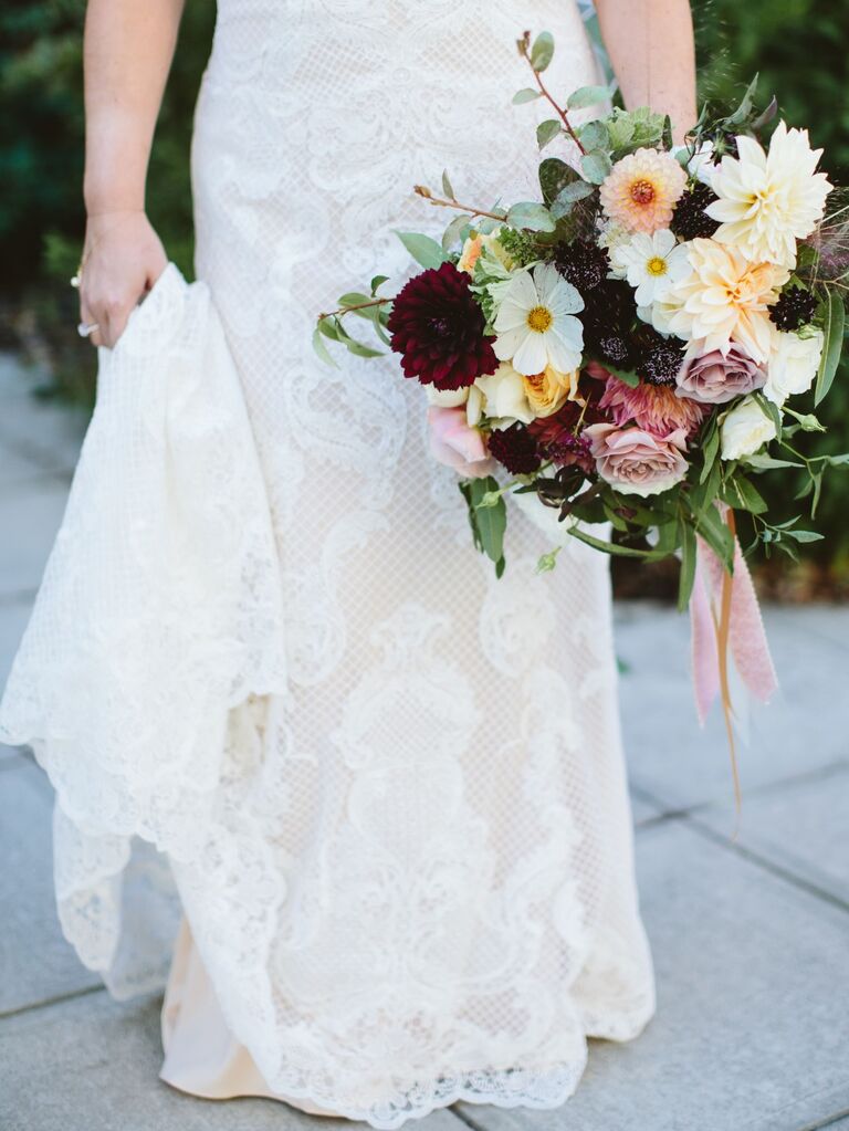 Bride holds a bouquet of dahlias and daisies. 