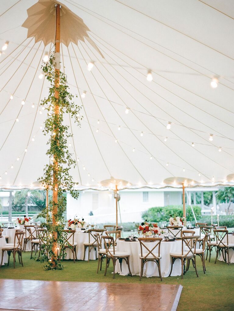 Center pole of tall wedding tent covered with garlands of greenery