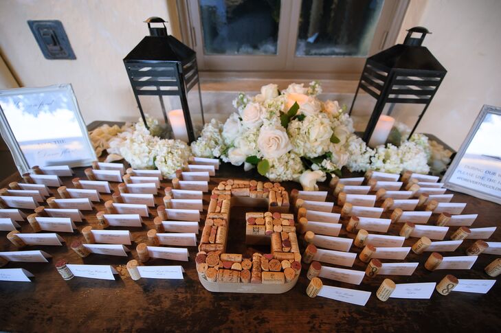 For a fun and unexpected twist, the couple decorated their escort-card display with wine corks. Each of the Melissa and Derek's 125 escort cards was paired with a wine cork, and the same accents formed their initial. Black lanterns and lush white florals also lined the table and complemented their centerpieces inside the reception.
