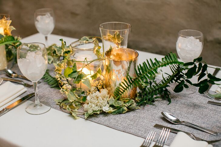 Amy Young of Leaves of Grass Floral Design was instrumental in the wedding’s design and transformed the raw industrial event space at Front and Palmer in Philadelphia, Pennsylvania, into an inviting and intimate backdrop. Warm candlelight incorporated throughout infused the room with undeniable ambiance, while natural elements like vines, ferns and an assortment of wispy pale blue and white wildflowers gave the decor a rustic, organic edge.