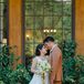 A bride in a long Marchesa A-line gown, a statement necklace, a small floral hair accessory and a wildflower bouquet embraces her groom in a pale burnt orange suit at a hotel in Yosemite.