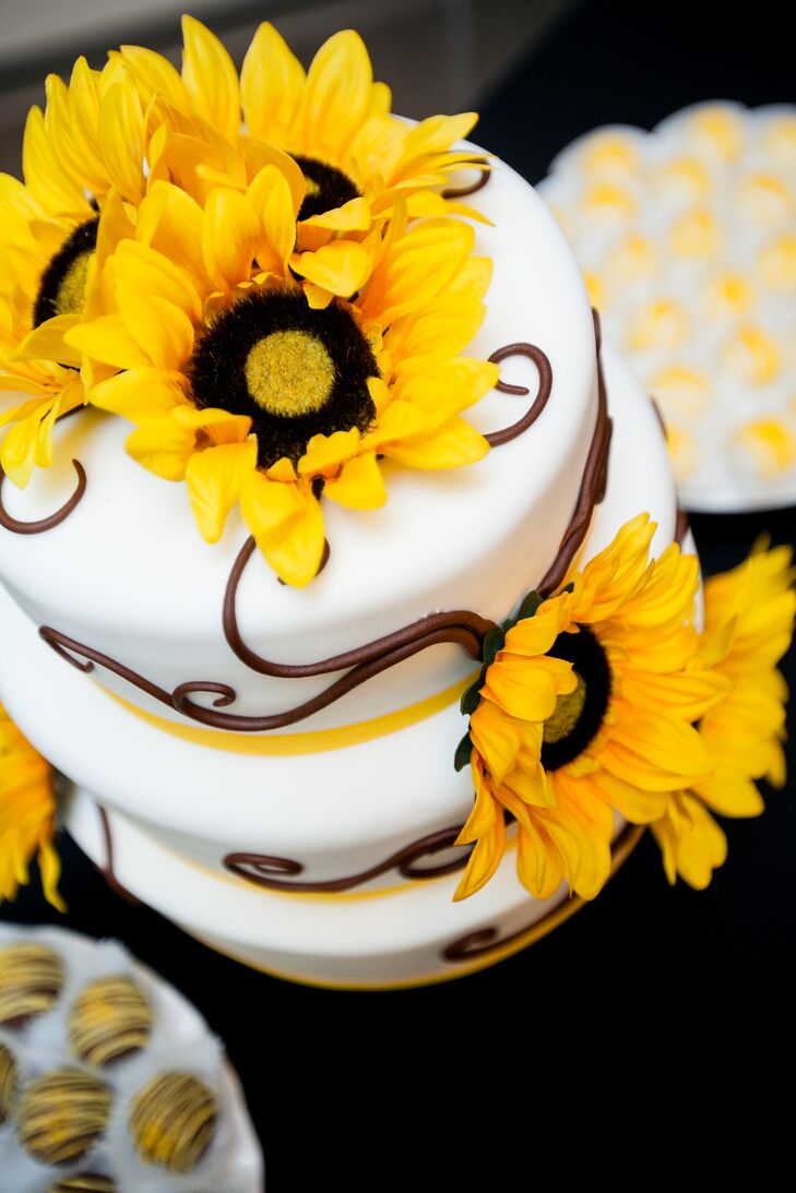 The three-tier wedding cake was decorated with brown piping, yellow ribbon and sunflowers. The cake had a different flavor for each tier.