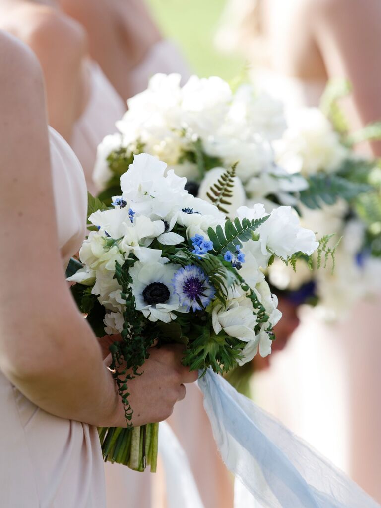 Bridesmaids hold bright blue and white flowers.