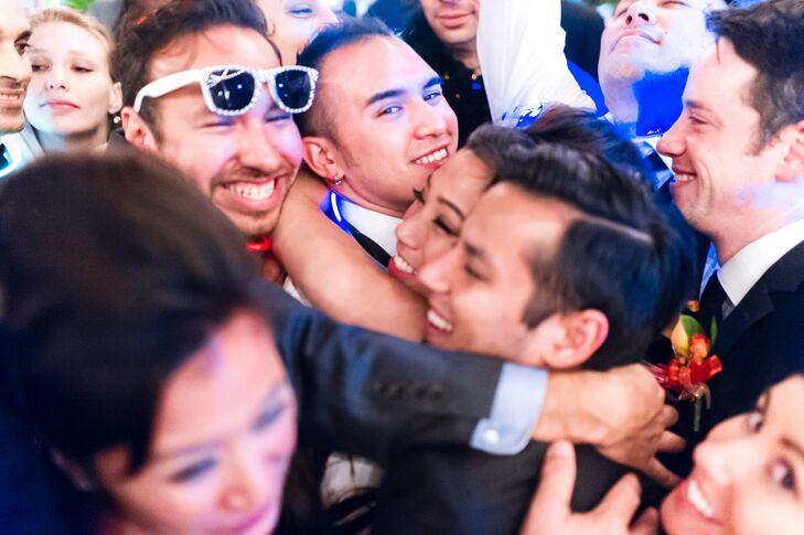 Bride and Groom Embrace on the Dance Floor Surrounded by Their Friends and Family
