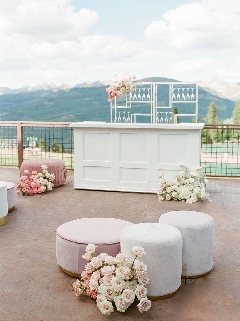 White outdoor bar space with velvet poofs.