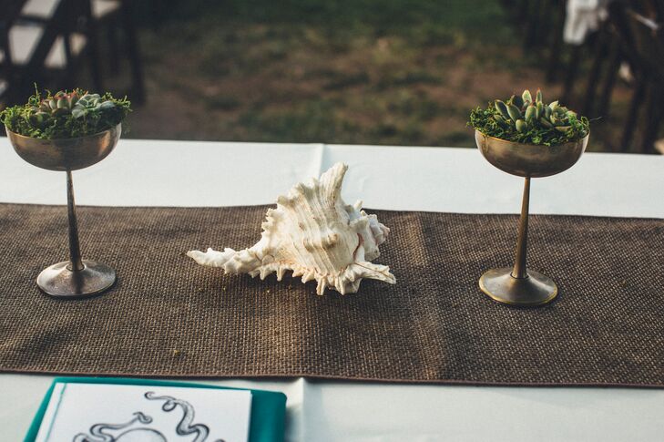 A large conch shell surrounded by gold vases with succulents decorated the dining tables dressed in burlap runners.