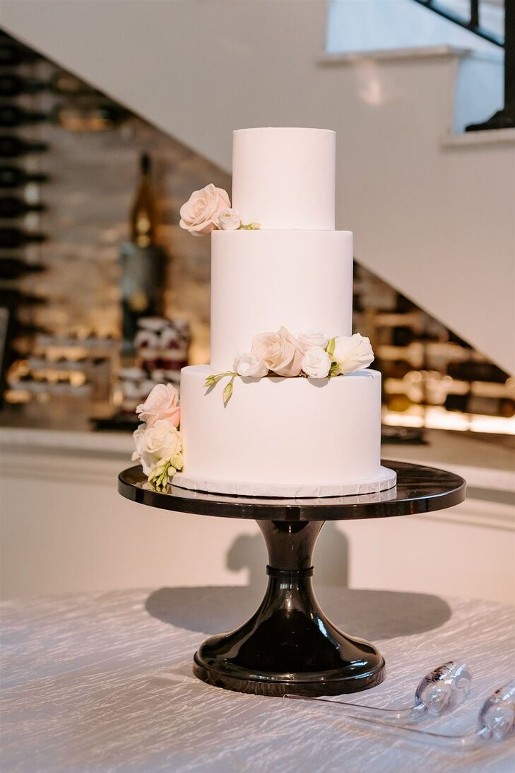 Elegant Three-Tier White Wedding Cake on Black Cake Stand