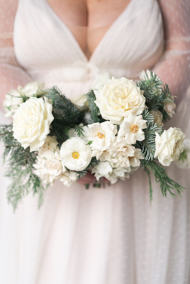 A winter-themed bridal bouquet for a Christmas wedding with white flowers and pine and cedar greenery.