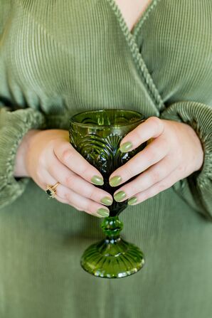Guest in Green Holds Green Wine Goblet at Wedding Reception