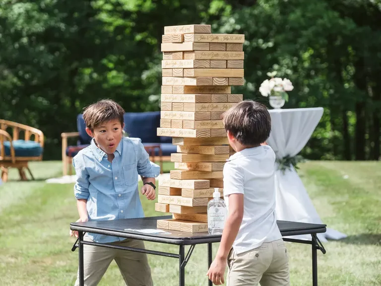 Two children playing oversized jenga at wedding reception