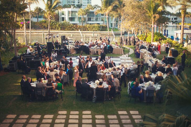 The couple decorated their outdoor garden reception with glass-topped round tables, gold linens, black chiavari chairs, a black and white checkerboard dance floor, string lighting, Great Gatsby-inspired art deco table numbers and gold accented floral centerpieces. “It was a magical and enchanted night for all,” says Amina.