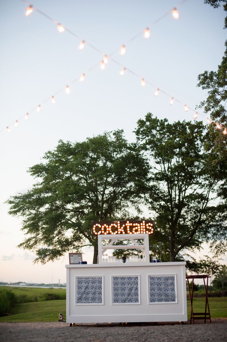 A modern bar with fun marquee lighting from 428 Main Vintage Rentals was set up outside for guests. The bar was decorated with navy damask fabric that matched their invitations and reception table settings.