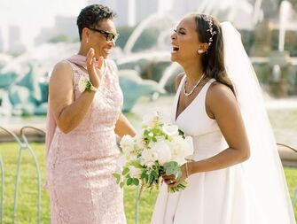 The bride and mother of the bride share a laugh together.