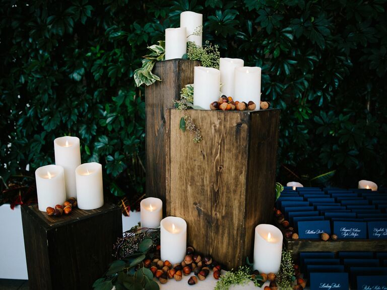 fall wedding decor idea with battery powered pillar candles and acorns on square wooden stands