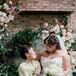 Bride in Half-Up Hairstyle Laughing With Bridesmaids in Varying Green Dresses