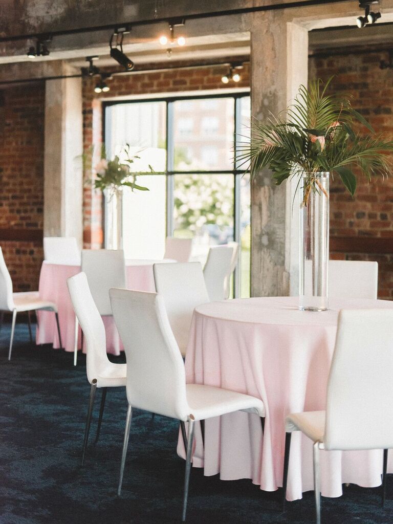 simple modern tall wedding centerpiece with glass cylinder vase and tropical greenery