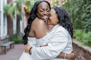 Two Brides in Different White Outfits Embracing With Big Smiles