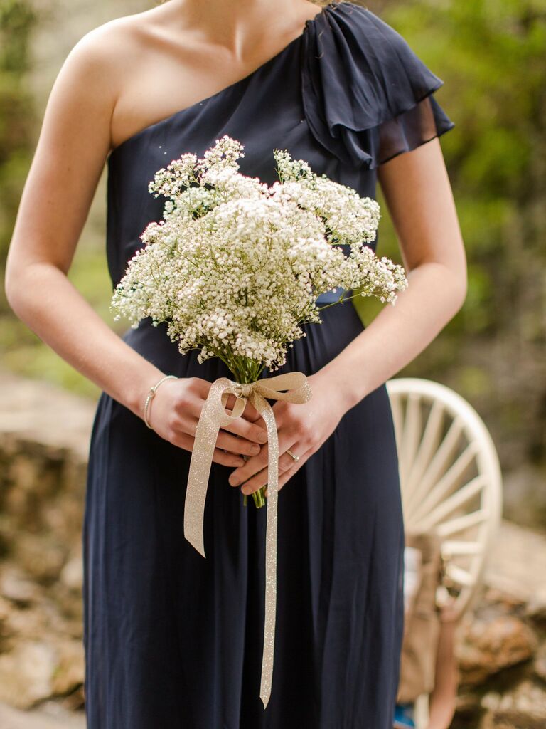 A bridesmaid holds a baby's breath bouquet.