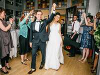 Bride and groom entrance at wedding reception with guests cheering