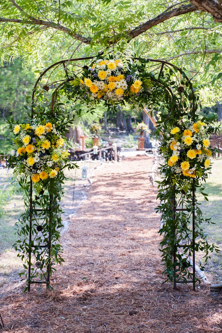This wedding arch, covered in yellow and white flowers with lots of greenery, framed the aisle entrance to Sarah and Bruce's outdoor Hill Country wedding.