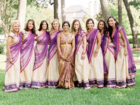 Bride and bridesmaid photo shoot wearing purple, green, and gold wedding saris. 