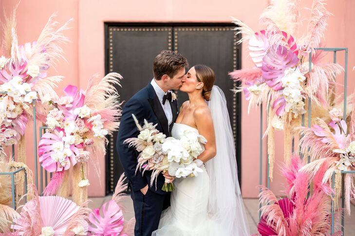Couple Shares a Kiss at Their All-Pink Ceremony Altar With Pampas Grass and Painted Palm Leaves