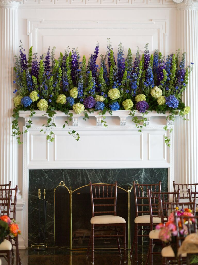 wedding fireplace decor with blue hydrangeas, purple delphinium, bells of ireland and ivy decorating a white mantel