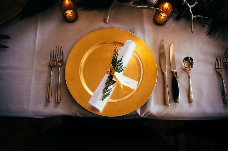 Suzi’s mother and brother tied all the flatware together with a gold satin ribbon, an evergreen branch and a textured gold calligraphy place card. They loved how the look fit the winter wedding season and the gold palette.