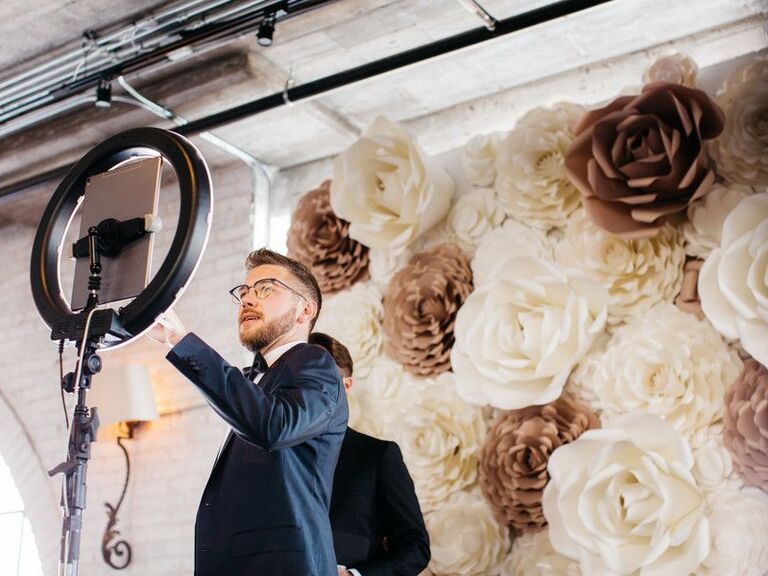 Guest taking selfie on iPad in front of faux flower wall