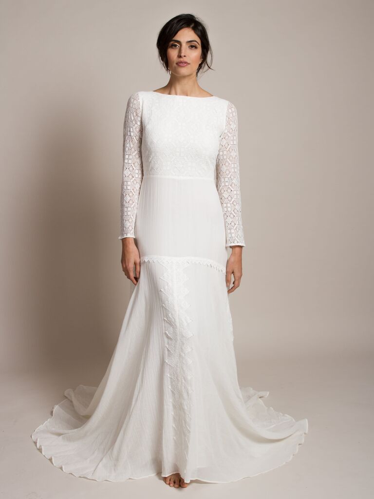 Model wears a long sleeve white wedding gown with a mermaid shape. 