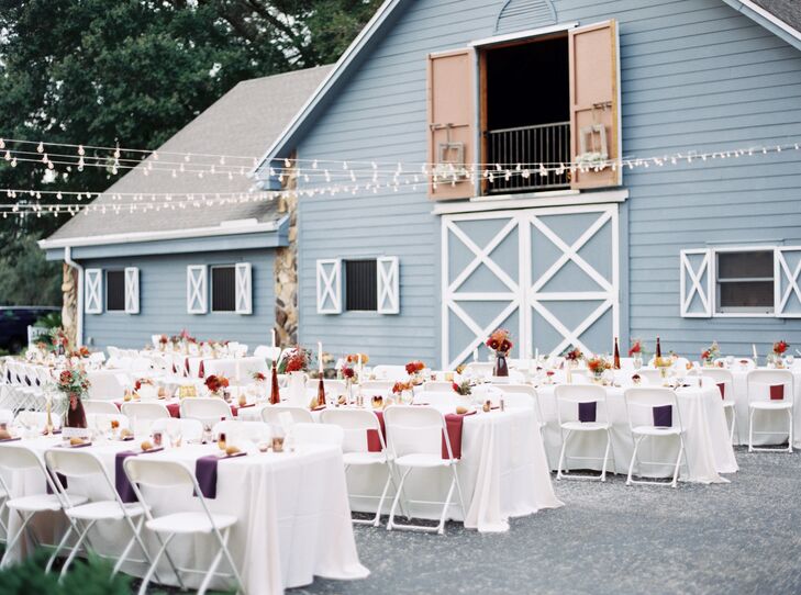While Shelby and Zack made sure every family-style table at their outdoor reception was a little different, they kept a few staples. White linens covered every table with burgundy or plum napkins and matching vases to bring in their fall theme. White folding chairs were also paired with each place setting.