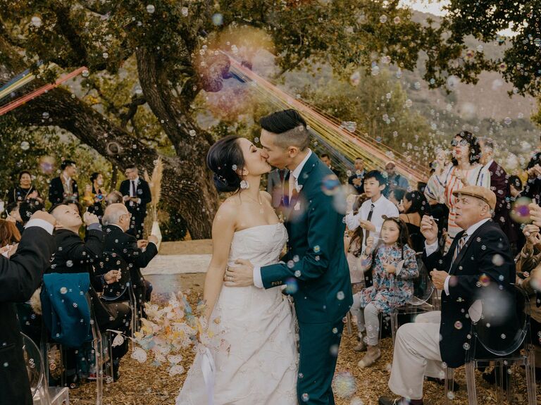 Newlyweds share a kiss at their whimsical outdoor recessional. 